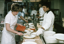 826816 Afbeelding van enkele medewerkers die maaltijden opscheppen in de vernieuwde centrale keuken van het ...